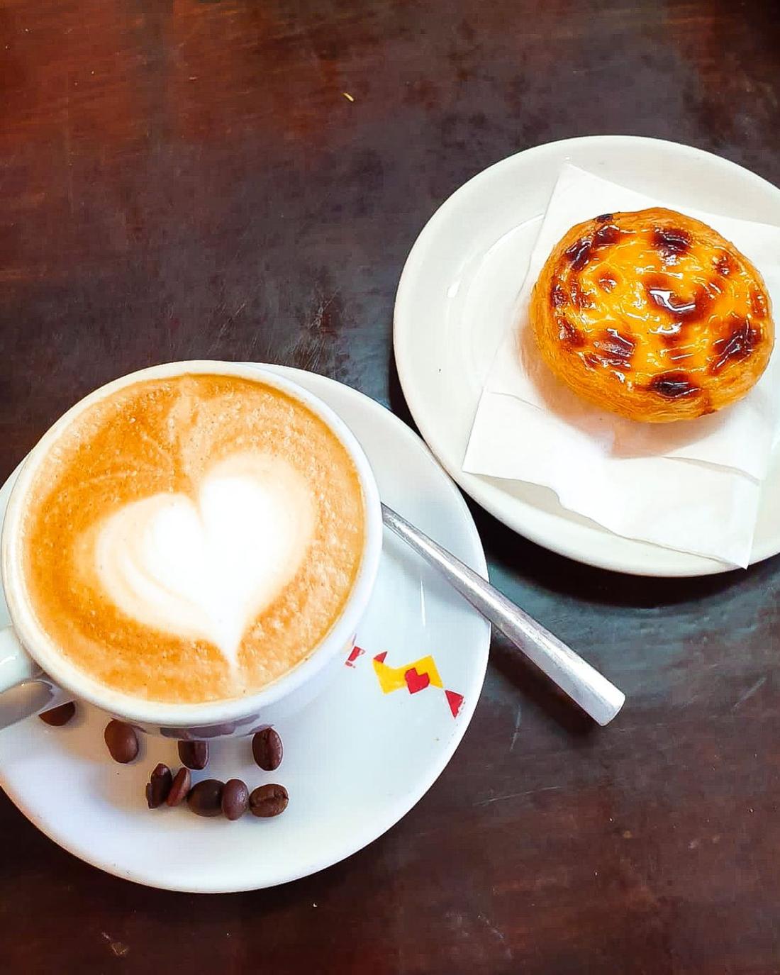A cappuccino with latte art and a pastel de nata